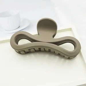 Minimalist large matte brown hair claw clip with elegant bow design on a clean white tray