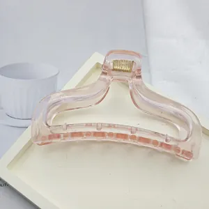 Detail view of a minimalist transparent pink hair claw clip placed on a white tray