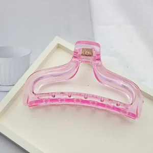 Detailed view of a transparent pink acrylic shark hair claw clip for women's styling