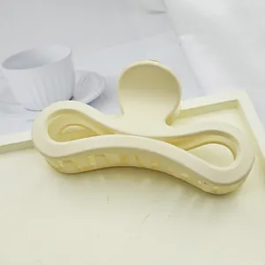 Close-up of large matte cream bow-shaped hair claw clip on a white tray
