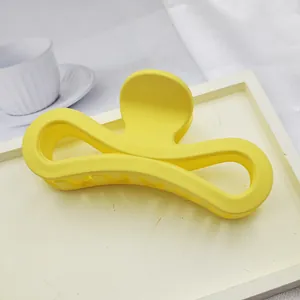 Close-up of large yellow matte hair claw clip with hollowed figure-eight design on tray