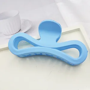 Detailed view of a large matte blue bow-shaped hair claw clip on a clean white tray