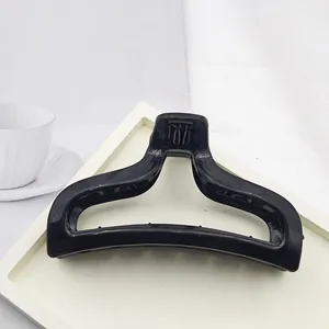Close-up of a minimalist large black hair claw clip on a chic white display tray