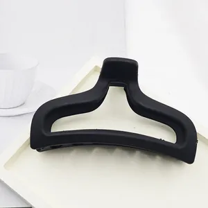 Macro view of a minimalist matte black shark hair claw clip on a clean white tray