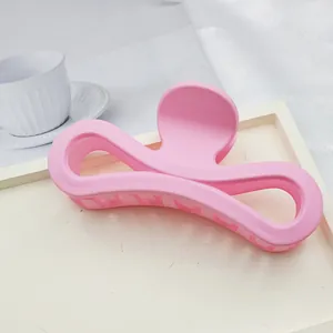 Detailed close-up of a pink matte infinity-shaped large hair claw clip on a white tray