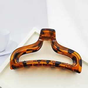 Detailed close-up of a large tortoiseshell acrylic hair claw clip on a white tray
