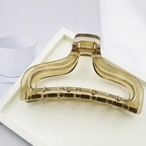 Detailed view of a minimalist amber translucent hair claw clip on a clean white tray