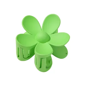 Detail view of a vibrant green matte flower-shaped hair claw clip on white backdrop