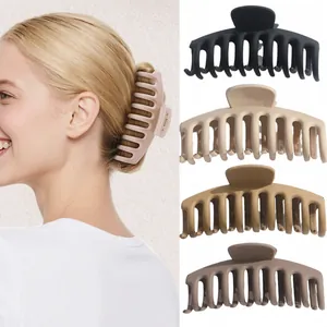 Large matte shark hair claw clips in neutral earth tones shown on a blonde model
