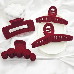 Close-up of four dark red velvet hair claw clips with elegant shapes and soft texture