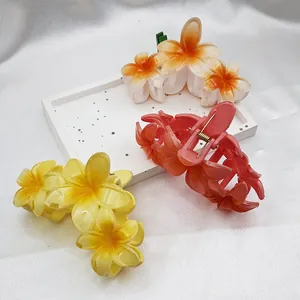 Detail view of vibrant plumeria flower hair claw clips in tropical summer vacation style