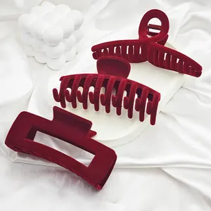 Close-up of three large burgundy velvet hair claws on elegant white silk background