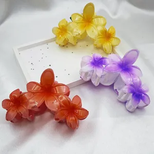 Close-up detail of vibrant frangipani hair claw clips in yellow, purple, and orange