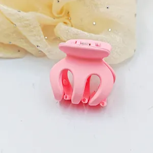 Close-up detail showing the matte finish and curved teeth of a pink mini hair claw clip