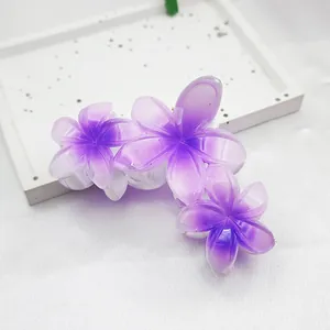 Macro view of purple plumeria hair claw clip showing translucent gradient petals