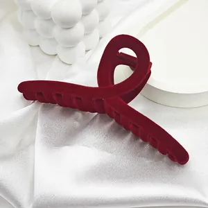Close-up detail of a large red velvet hair claw clip with an elegant twisted design