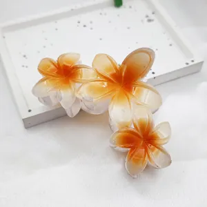 Close-up detail of tropical frangipani flower hair claw clip with orange gradient petals