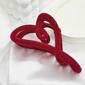Detailed macro view of a large red velvet heart-shaped hair claw clip on white fabric.