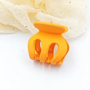 Detailed view of a small orange matte hair claw clip for high ponytail styling accessories