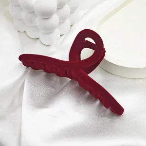Detailed view of a large burgundy red velvet hair claw clip placed on white silk fabric