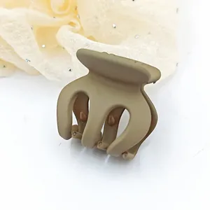 Close-up macro view of small khaki matte hair claw clip against cream rhinestone fabric