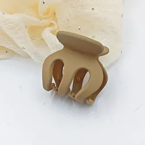 Detailed view of a small matte brown plastic hair claw clip for elegant hair styling.
