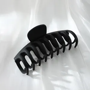 Macro view of a professional large matte black hair claw clip on white silk background