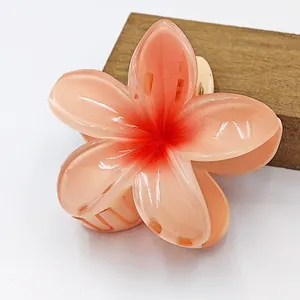 Κοντινό πλάνο ενός κλιπ μαλλιών Plumeria σε χρώμα ροδάκινου με γυαλιστερό φινίρισμα