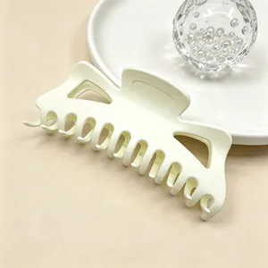 Close-up detail view of a large minimalist matte cream hair claw clip for thick hair styling