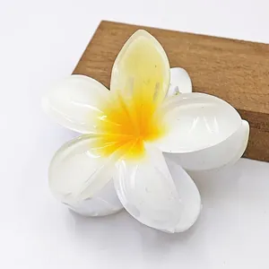 Λεπτομερής άποψη ενός λευκού και κίτρινου κλιπ μαλλιών από ρητίνη σε σχήμα λουλουδιού Frangipani