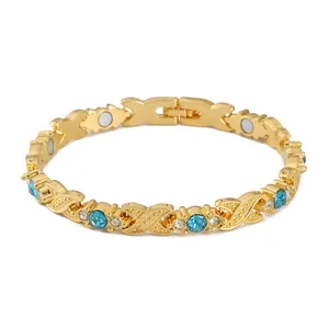 Gold-toned magnetic bracelet with blue rhinestones and X-shaped links on a white background