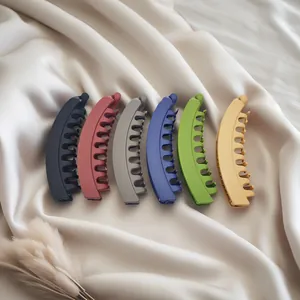 Close-up view showing six colorful matte banana hair clips arranged on soft silk fabric