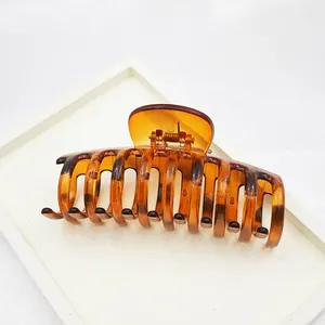 Detailed view showing the glossy texture and metal spring of a leopard print hair claw clip