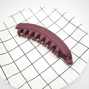 Macro detail view of a large matte burgundy banana hair clip for thick hair styling