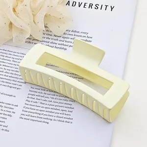 Macro view of a matte cream square hair claw clip placed on a book page with English text