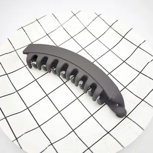 Side view of a large matte grey banana hair clip on a minimalist grid background