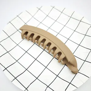 Matte light brown banana hair clip for thick hair shown on a grid pattern plate