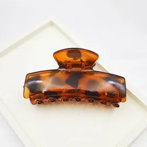 Large tortoise shell leopard print hair claw clip made of amber translucent plastic material