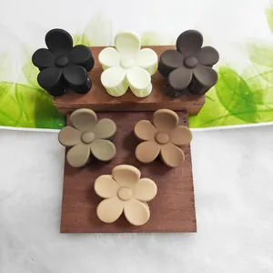 Detailed view of six matte flower-shaped hair claw clips in various earth tones