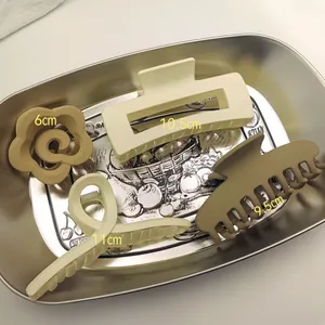 Detailed view of four minimalist matte hair claw clips with size markings on a metal tray.