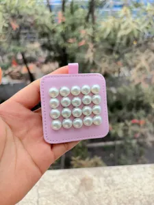 Detalle de pendientes de perlas magnéticos sobre una base de cuero rosa elegante