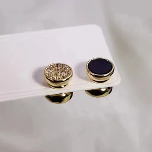 Vista macro de pendientes magnéticos dorados con pavé de cristal y detalle negro