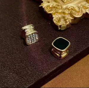 Vista detallada de pendientes magnéticos de lujo dorados con esmalte negro y pavé cristal.