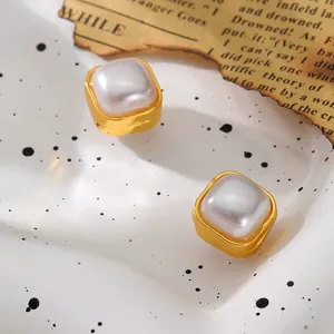 Primer plano de elegantes pendientes de clip magnéticos cuadrados dorados con perlas.