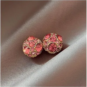 Close-up of elegant pink rhinestone ball earrings on a luxury brown satin background.