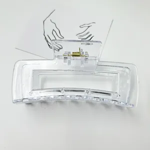 Macro view of a large clear rectangular hair claw clip with golden metal spring