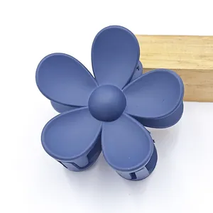 Close-up of a matte navy blue five-petal flower hair claw clip with a shark clip design.