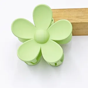 Close-up of matte pale green five-petal flower hair claw clip with smooth texture