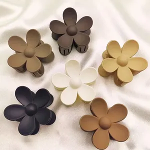 Detailed shot of large matte flower hair claw clips in various elegant earth-tone colors