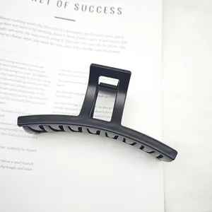 Pinza de pelo negra mate minimalista para cabello grueso mostrada en un libro